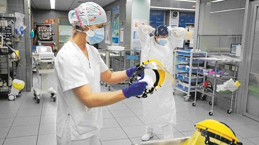 Una enfermera ayuda a quitarse el EPI a una compañera. FOTO: Pere Ferré