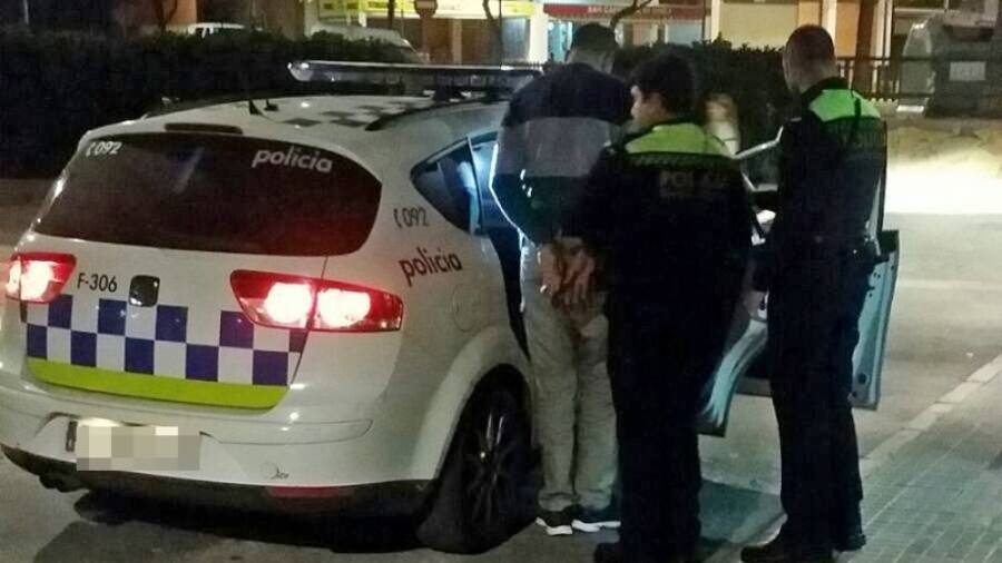 Dos agentes de la Guàrdia Urbana introduciendo al detenido en el vehículo policial. Foto: María Ortega