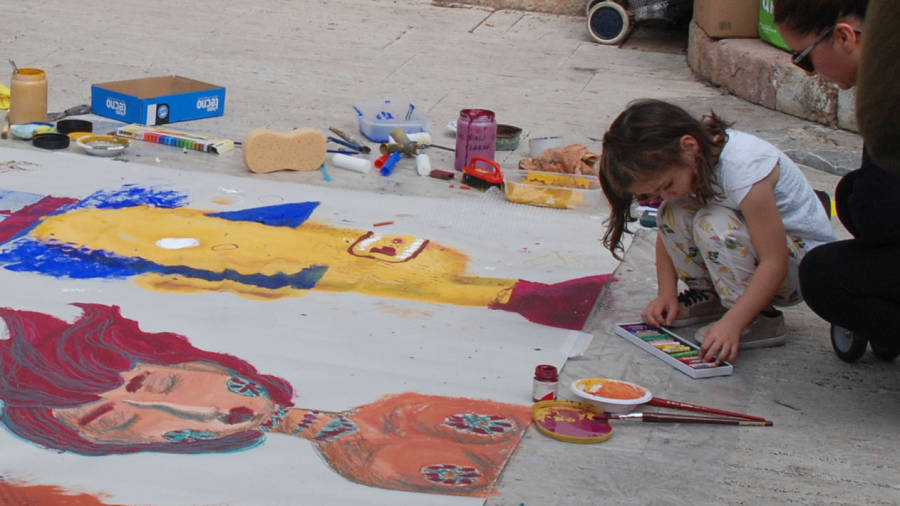 Una nena pintant un mural.