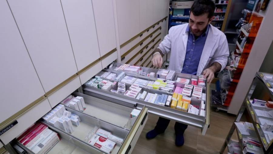 Un empleado, junto a un cajón de medicamentos, en una farmacia de Tarragona. FOTO: LLUÍS MILIÁN