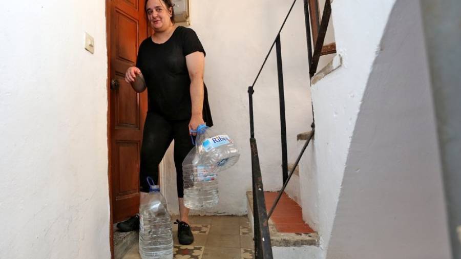 Imagen de una de las vecinas entrando a casa con las garrafas de agua de la fuente. Foto: Lluís Milián