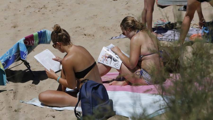 Dos jóvenes toman el sol a mediodía en la playa de Capellans en Salou. Los psicólogos defienden que cada uno tiene que aceptar el color natural de su piel sin dejarse llevar por modas. Foto: pere ferré