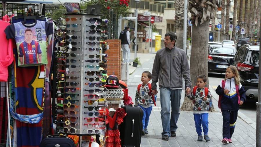 Un hombre con tres niños pasa por delante de un establecimiento multimarca, en la calle Barcelona de Salou. Foto: Pere Ferré