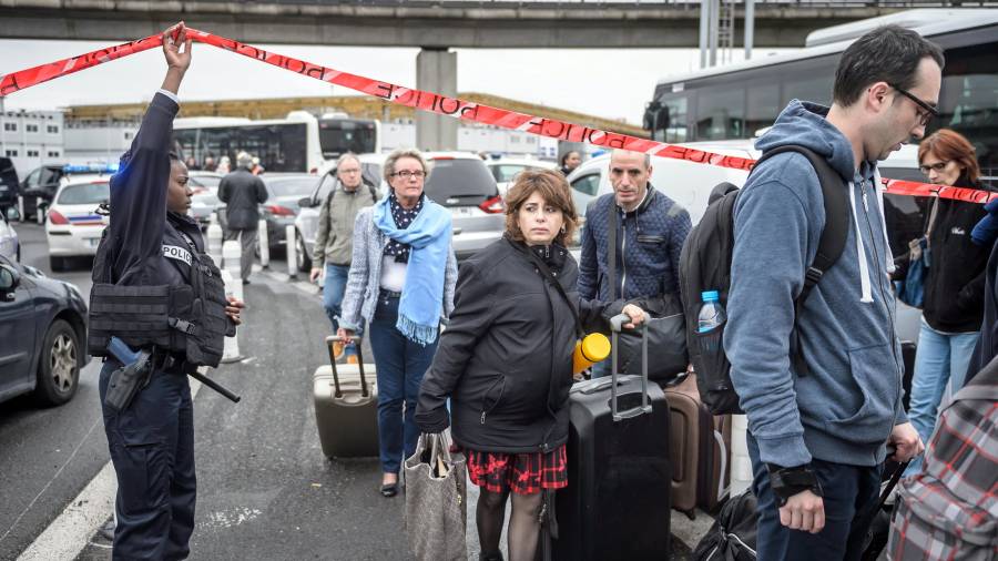 Pasajeros evacuados ayer del aeropuerto parisino de Orly caminan por la autopista con sus maletas. FOTO: EFE FOTO: EFE