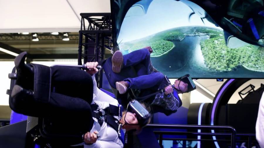Dos visitantes prueban un simulador de vuelo acrobático de realidad virtual en el stand de la empresa coreana Samsung en el Congreso Mundial de Móviles, (MWC, en sus siglas en inglés), que hoy vive su segunda jornada. EFE/Alberto Est&