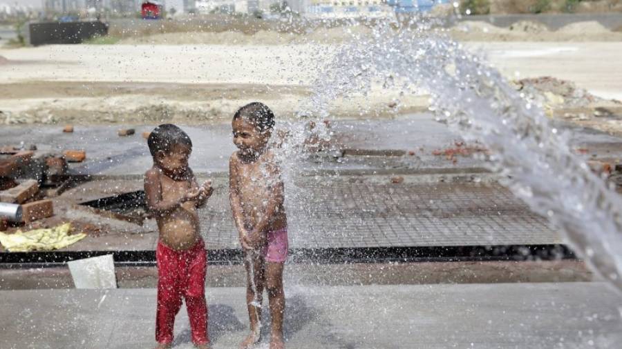 Dos niños se refrescan con una manguera durante uno de los días más calurosos en Nueva Delhi, el pasado mes de abril. Foto: EFE