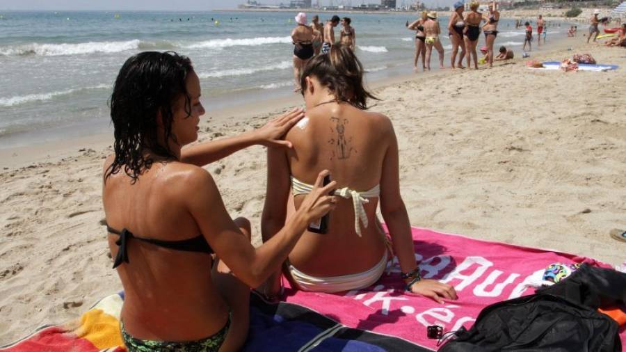 Dos jóvenes se protegen del sol con crema para evitar que las radiaciones ultravioletas puedan afectar a la piel, una de las zonas sensibles. FOTO: LL.MILIÁN