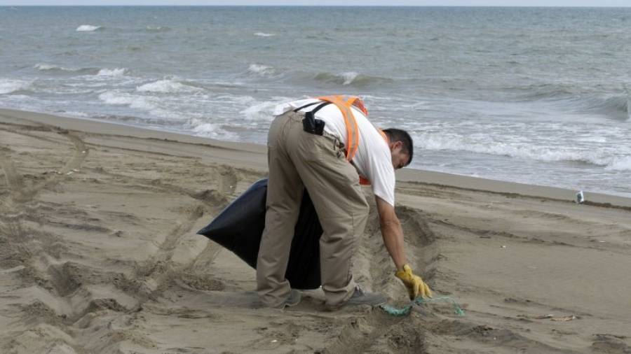 Un home recollint deixalles en una platja del Delta. Foto: Joan Revillas