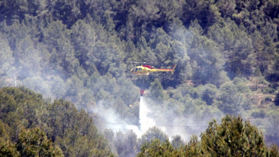 Un helicòpter dels Bombers descarregant aigua sobre la columna de fum de l'incendi. Foto: ACN