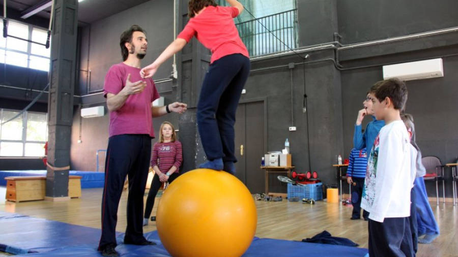 Un dels alumnes, durant el taller de circ, fent equilibris damunt d'una pilota. Foto: ACN