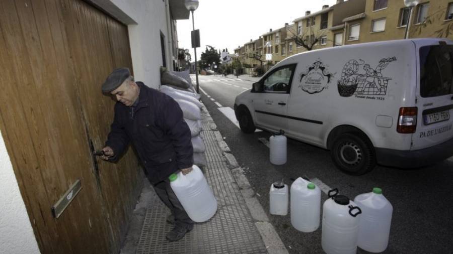 Un veí de l'Aleixar carregat amb ampolles d'aigua entrant a casa seva. Foto: Alba Mariné