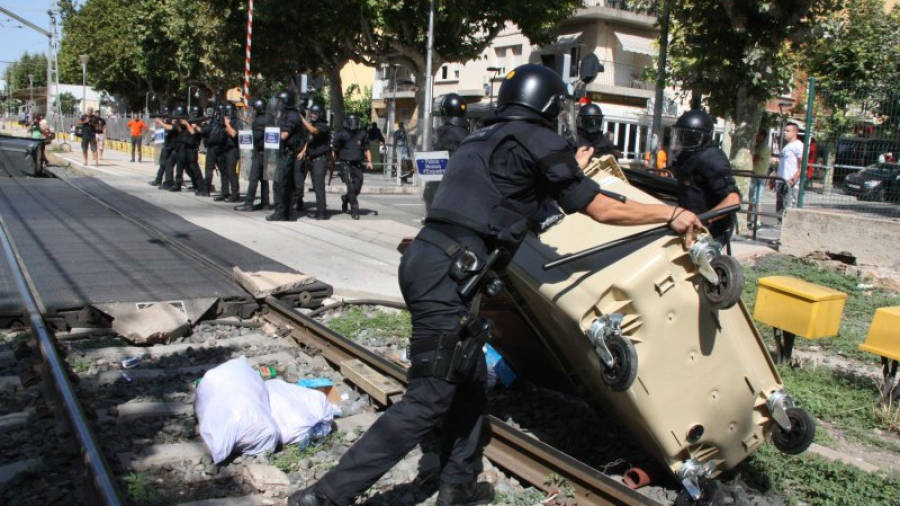 Un agent dels Mossos d'Esquadra retirant un contenidor del mig de la via del tren a Salou. Foto: ACN