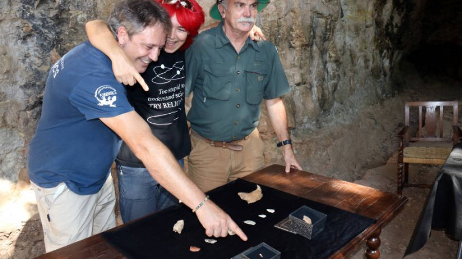 Els arqueòlegs Eudald Carbonell i Jordi Rosell juntament amb l'arqueòloga que va fer la troballa de la dent assenyalant-la al taulell on hi ha la resta de troballes de la campanya a la Cova de les Teixoneres de Moià, el 20 d'agost de