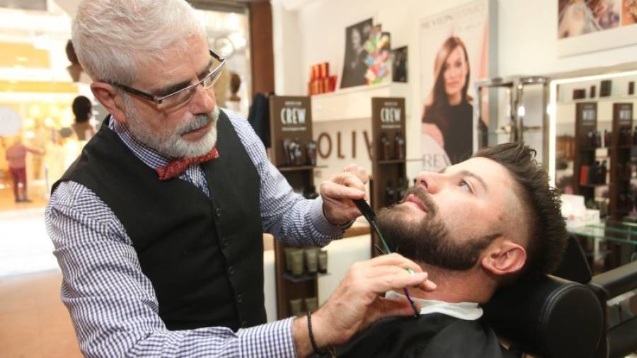 El perruquer Manel Oliva mentre retalla una barba. Foto: alba mariné.