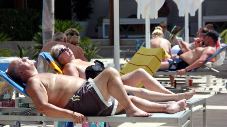 Una parella de turistes estrangers prenent el sol en unes gandules, junt amb altres turistes a la zona de piscina en un renovat ressort de la Costa Daurada, a Cambrils, el 21 de juny de 2016.