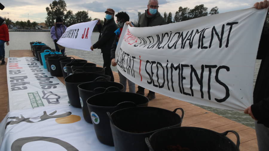 Els manifestants amb cabassos plens de sediments que s'han abocat al riu Ebre en el marc d'una acció simbòlica a Deltebre. ACN