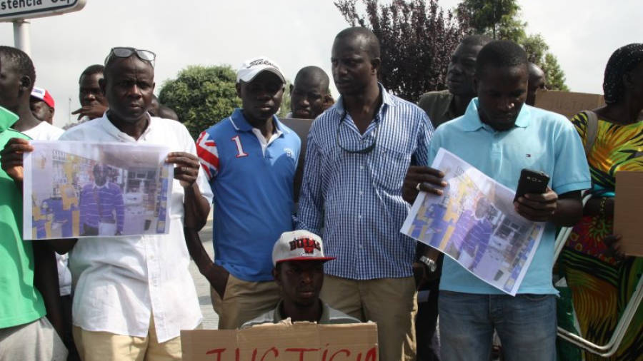 Ibrhymma Sylla, germà de l'home senegalès mort, amb camisa a quadres, en la concentració de dimecres, amb cartells que reclamen justícia i fotos de la víctima. Foto: ACN