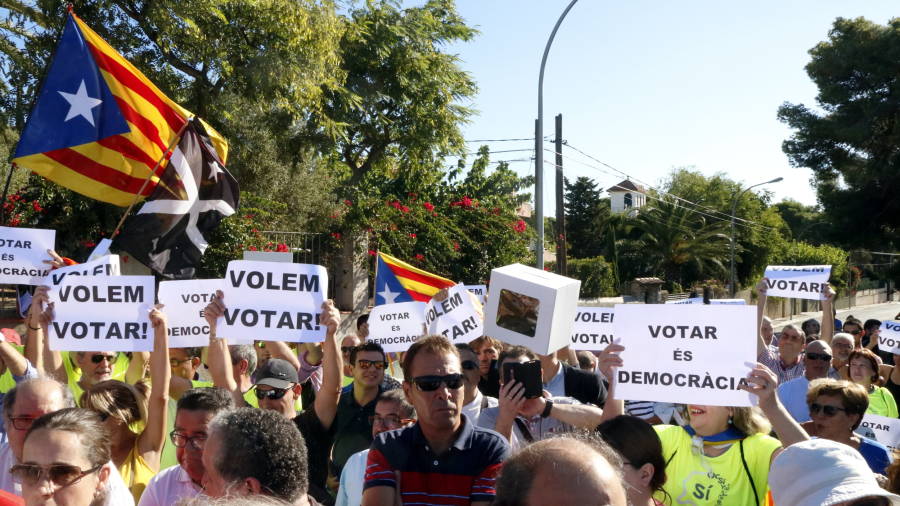 Pla obert de diverses persones exhibint pancartes reclamant poder votar en l'acte institucional de la Diada a Tarragona. Foto: ACN