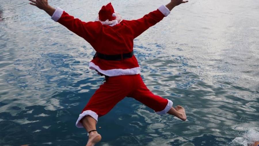 Un participante disfrazado de Papá Noel se lanza al agua para participar en la 111º edición de la Copa Nadal, que este año se celebró rodeada de medidas sanitarias a causa de la pandemia de Covid-19, en Barcelona. EFE/Alejandro García