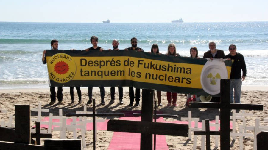 Els ecologistes han clavat creus a la sorra de la platja del Miracle de Tarragona i han desplegat una pancarta pel tancament de les centrals nuclears. Foto: ACN