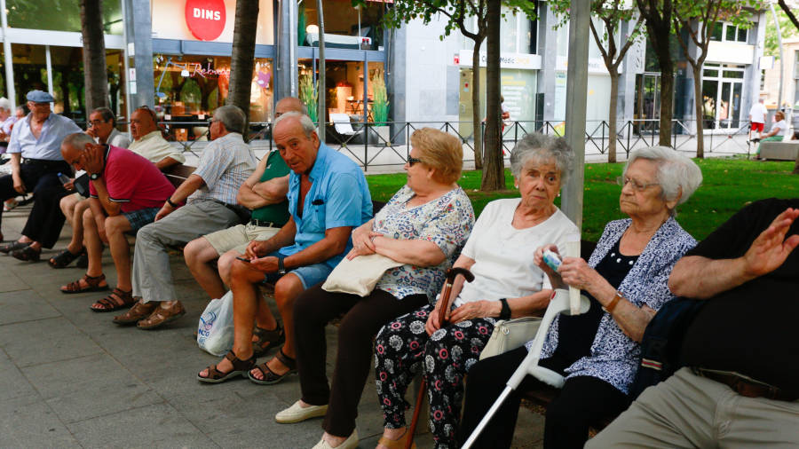 Un grupo de personas mayores, sentados durante la tarde en unos bancos, en la Plaça Llibertat de Reus. FOTO: FABIÁN ACIDRES
