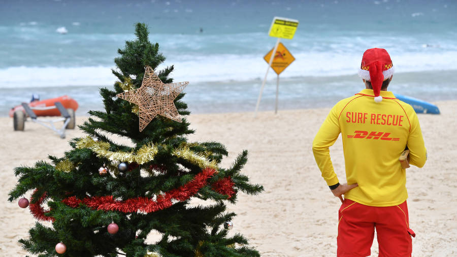 Esta&nbsp;Navidad un&nbsp;socorrista vigila la playa junto a un árbol de Navidad, en una ventosa y lluviosa mañana en la playa de Bondi, en Sídney (Australia). EFE/MICK TSIKAS