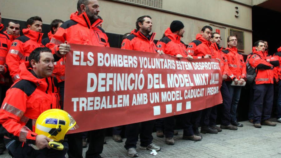 Bombers voluntaris de la Regió d'Emergències de Tarragona han desplegat una pancarta denunciant la seva situació a les portes de la Delegació del Govern. Foto: ACN