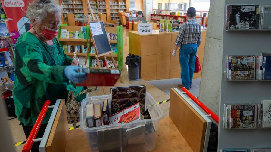 Una usu&agrave;ria deixant els llibres per tornar a la capsa que s'a&iuml;llar&agrave;. Foto: J. Revillas