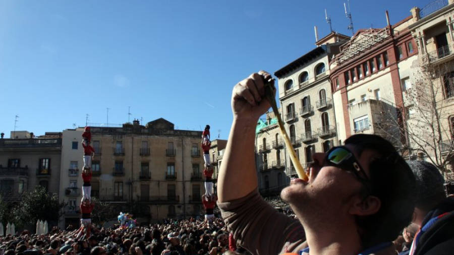 El guanyador del concurs de menjar calçots, el lleidatà Josep Maria Gòdia, menjant-se una ceba amb els pilars de les dues colles castelleres vallenques al fons. Foto: ACN