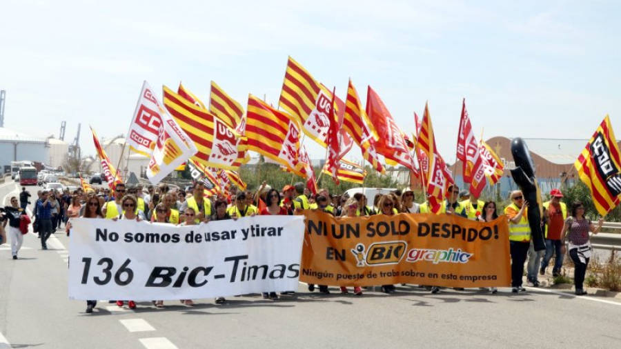 Pla general dels treballadors de BIC Graphic a Tarragona, fent una marxa lenta encapçalada per pancartes de protesta a l'autovia de Salou