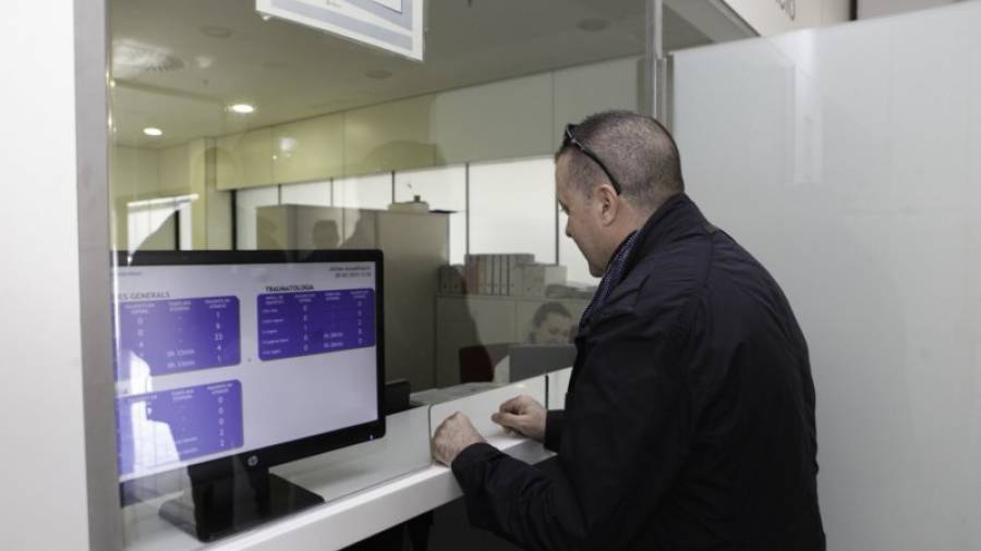 Un usuario del servicio de Urgencias del Hospital Sant Joan. A su lado, la nueva pantalla que informa sobre los tiempos de espera. Foto: Alba Mariné