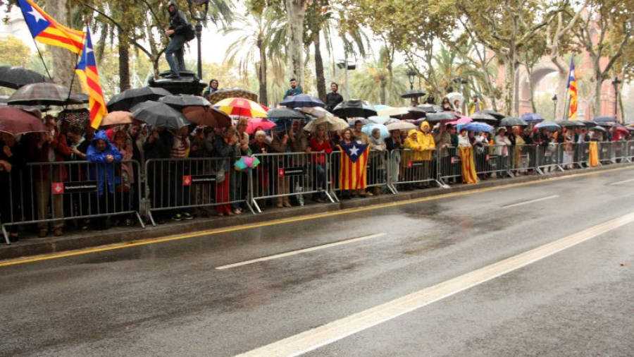 Alguns dels ciutadans que, aixoplugats sota els paraigües, han acudit a donar suport a Joana Ortega a les portes del TSJC. Foto: ACN