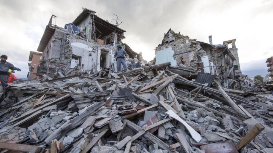 Los equipos de búsqueda y rescate trabajan entre los escombros de un edificio en Amatrice, en el centro de Italia