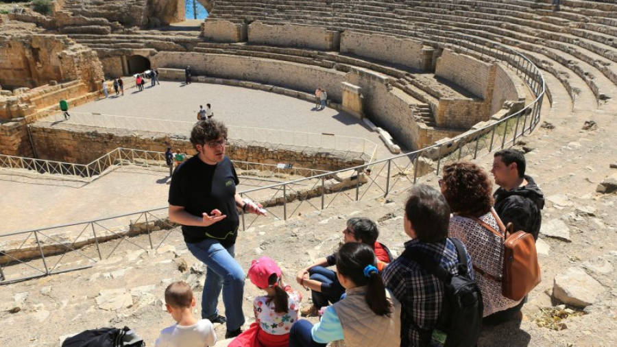 Pla obert de diversos turistes, d'esquena, gaudint d'una visita guiada a l'amfiteatre de Tarragona. Imatge de l'edició 2015 del Tarragona Family Week.
