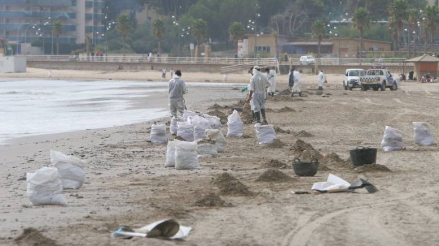 Operarios limpiando con palas el crudo de la playa. Foto: Lluís milián
