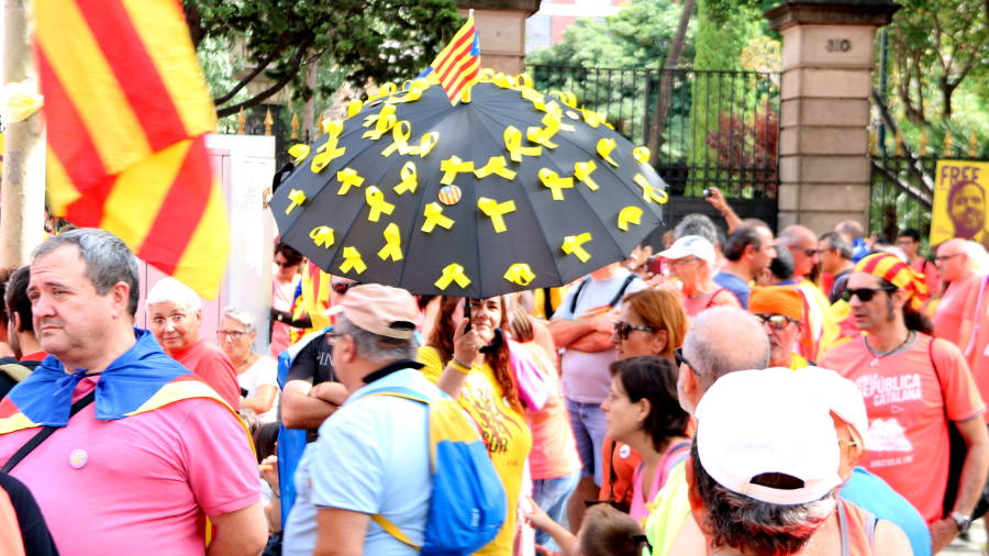 Pla general d'una manifestant amb un paraigua ple de lla&ccedil;os grocs a la manifestaci&oacute;. FOTO: ACN