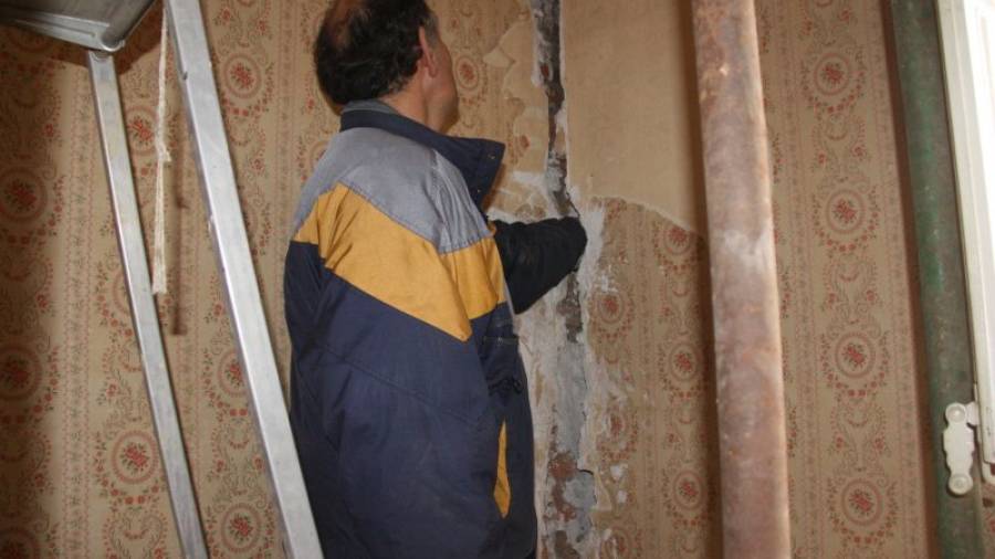 El veí Ramon Ribas, introduint tota la mà sencera dins l'esquerda que destrossa casa seva. Foto: ACN