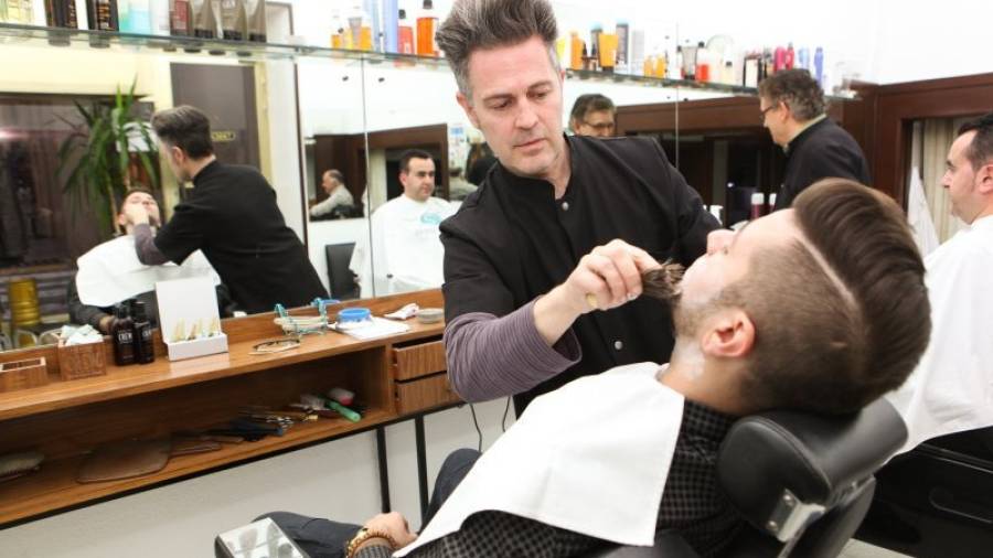Javi Torrente, arreglando la barba a un cliente en la barbería Casado Torrente, en la calle Hospital. Foto: alba mariné