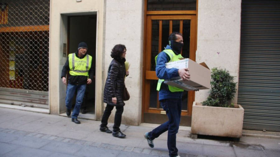 Agents de la Guàrdia Civil surten d'un dels domicilis registrats amb una caixa al carrer la Cort de Valls el 19 de febrer de 2016. ACN