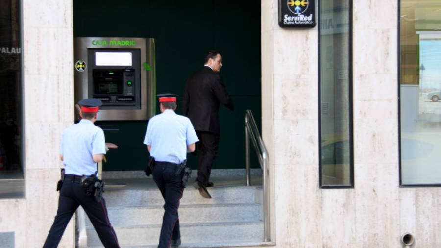 Dos agents dels Mossos conversen a l'interior de l'oficina de Bankia d'Amposta durant la visita del secretari judicial. Foto: ACN