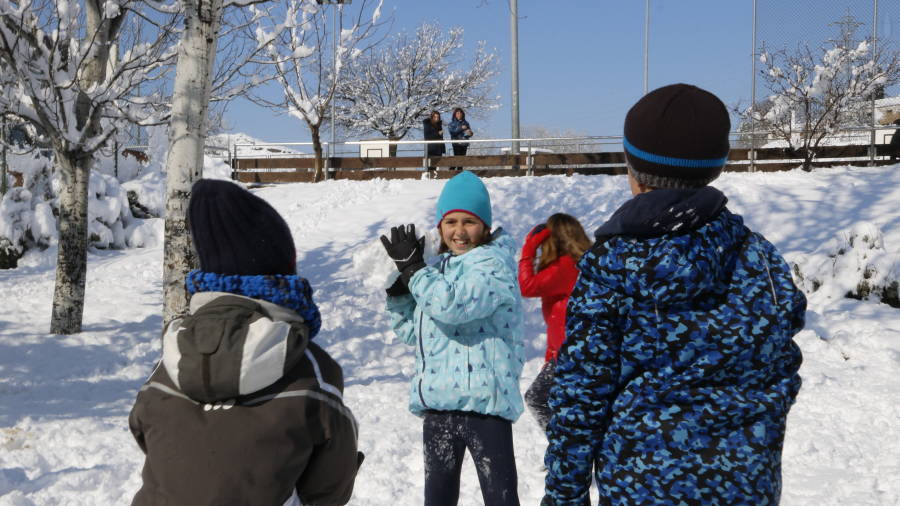 Una nena est&agrave; a punt de llan&ccedil;ar una bola de neu als seus companys, mentre juguen al pati de l'escola Guillem de Mont-Rodon de Vic.