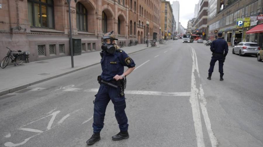 Miembros de la policía sueca se ajustan las máscaras antiguas en la zona donde un camión que ha atropellado a varias personas y se ha estrellado contra una tienda de la calle comercial de Drottninggatan en el centro de Estocolmo. EFE