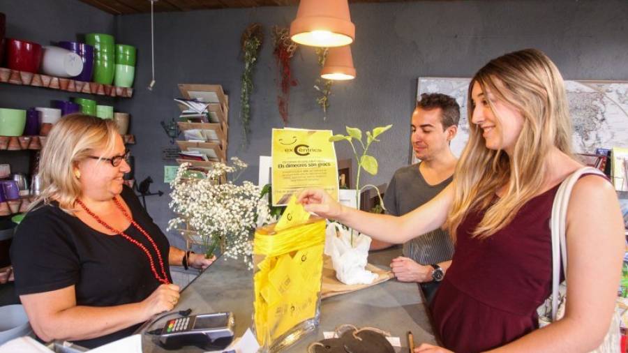 Unos clientes introducen su boleta en la urna para participar en el sorteo, en el Centre Botànic. Foto: ALBA MARINÉ