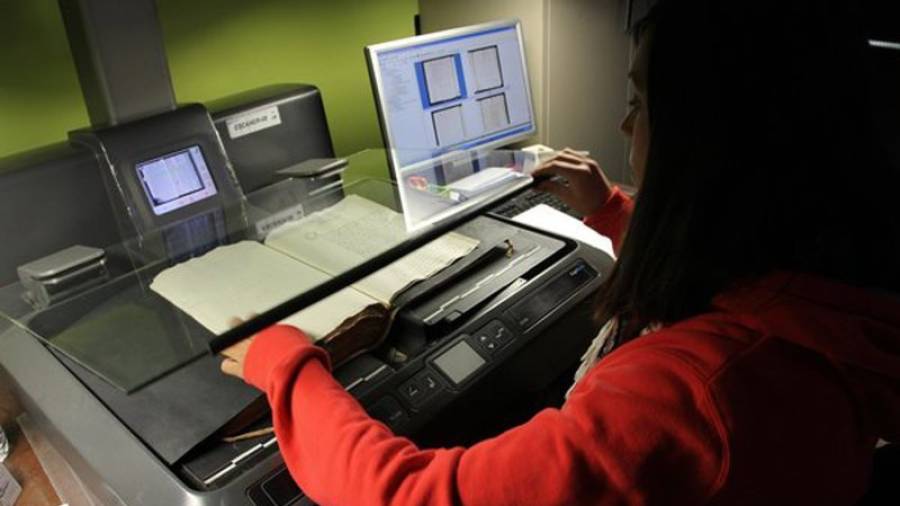 Treballadora digitalitzant documents amb l'escàner aeri. Foto: AHAT