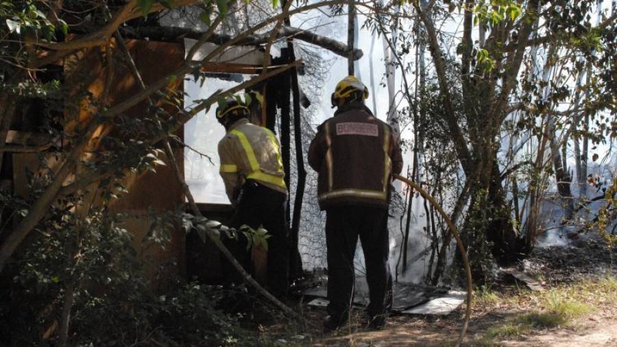 Dos bomberos accediendo a uno de los huertos afectados por el incendio. Foto: Àngel Juanpere