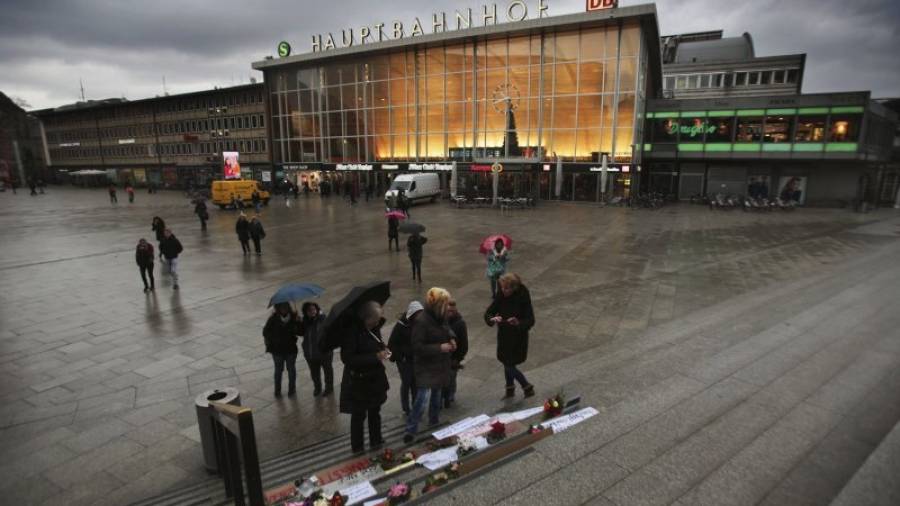 Un grupo de transeúntes obseva los carteles y pancartas colocadas en la estación principal de Colonia (Alemania) el 11 de enero de 2016. La policía de Colonia informó de que el número de denuncias presentadas por presunt