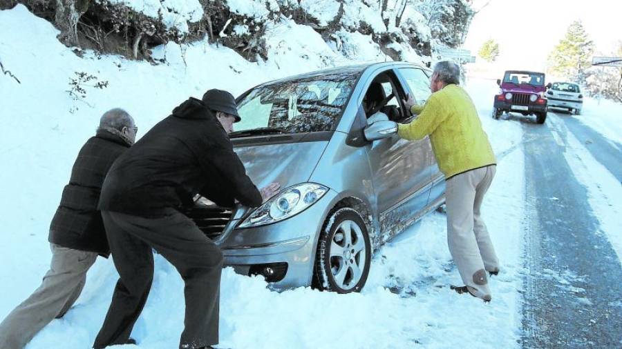 Diverses persones intenten moure un cotxee encallat per la neu a la cuneta de la carretera entre Vimbodí y Vilanova de Prades. FOTO: PERE FERRÉ