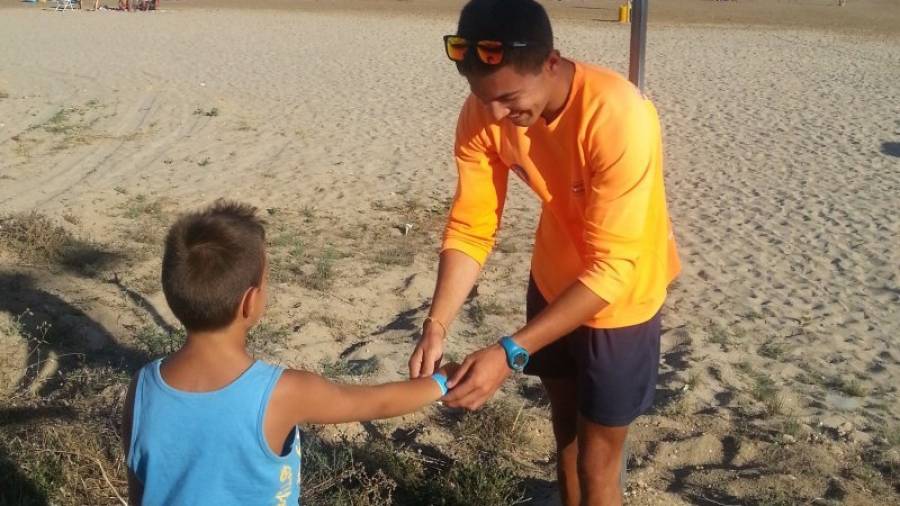 Un socorrista coloca una pulsera identificativa a un niño en una playa, en una imagen de archivo. Foto: DT