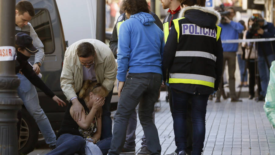 En la foto, la cuñada del fallecido en el lugar del tiroteo siendo atendida por amigos y la policía. FOTO: MARISCAL/EFE