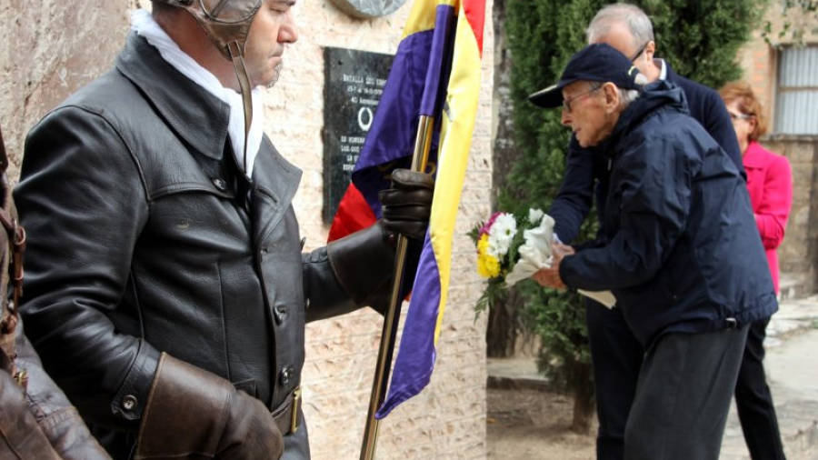 Antoni Vilella, un dels mecànics de la secció d'aviació de la República diposita un ram de flors al monuments als aviadors del parc de la Bassa de Gandesa davant un soldat d'un grup de recreació històrica que mant